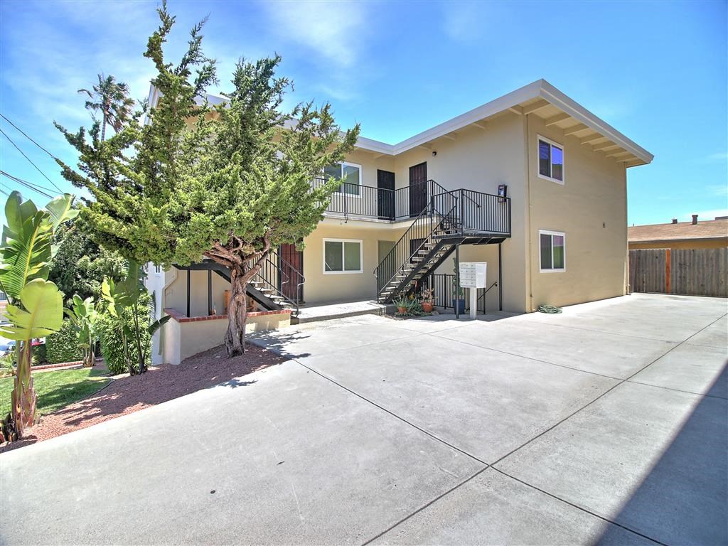 a yellow house with a driveway and a tree in front of it