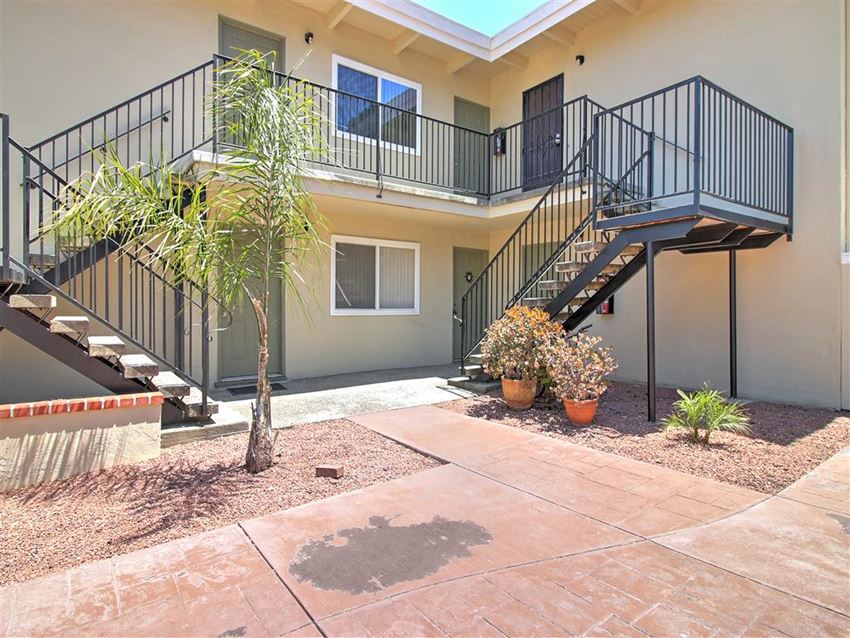 a building with a staircase and a palm tree in front of it