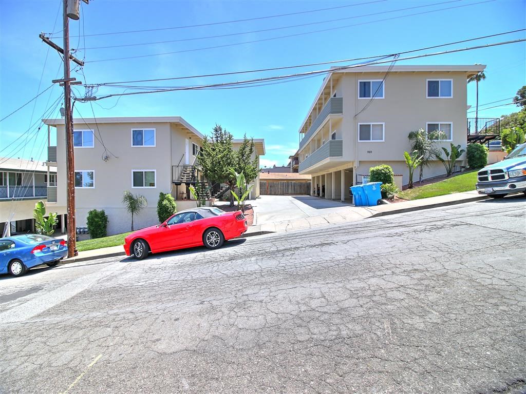 a red car parked on a street in front of apartments