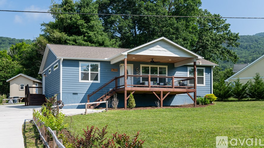 A blue house with a porch and a mountain in the background.