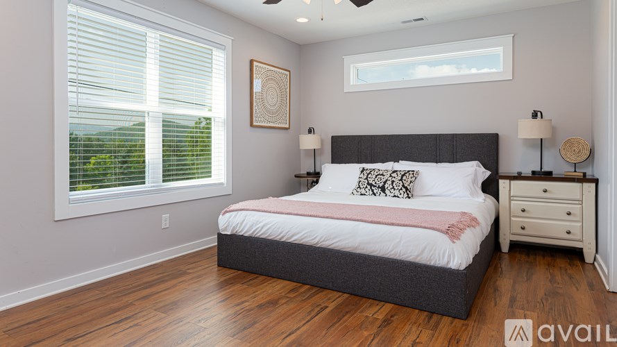 A bedroom with a large bed, a nightstand, and a window with blinds.