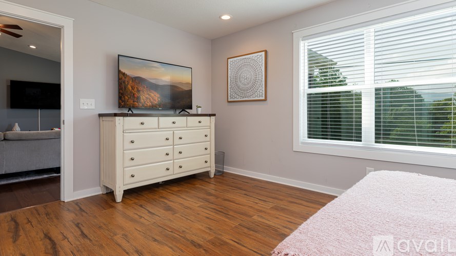 A bedroom with a dresser and a painting on the wall.