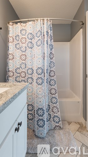 A bathroom with a shower curtain and a white cabinet.
