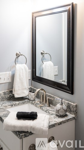 A bathroom with a marble countertop and a mirror reflecting the same scene.