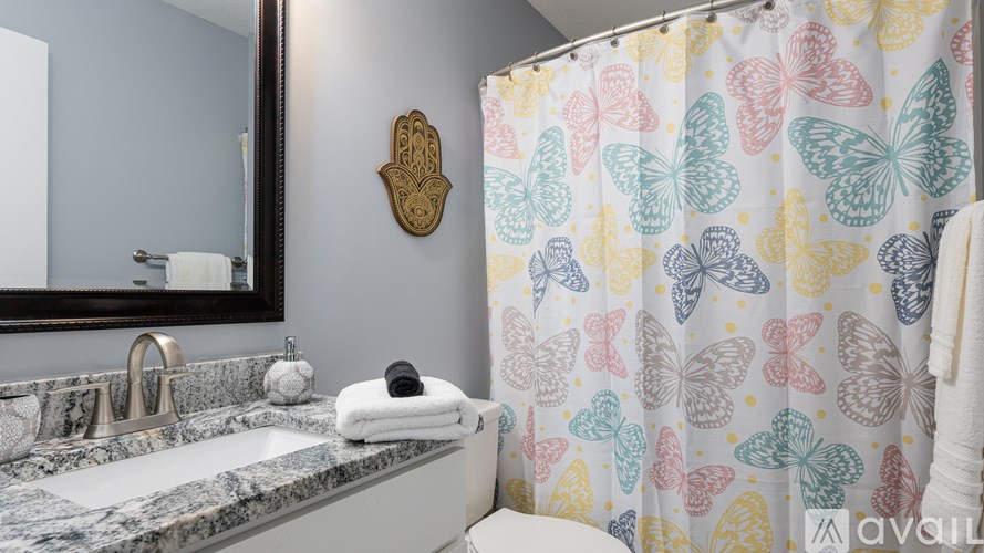 A bathroom with a shower curtain and a mirror.