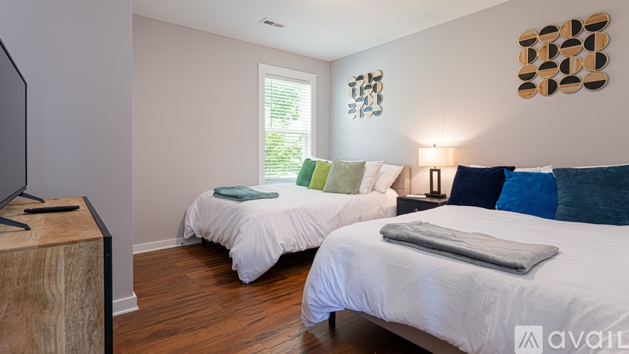 A bedroom with two beds and a television on a wooden stand.