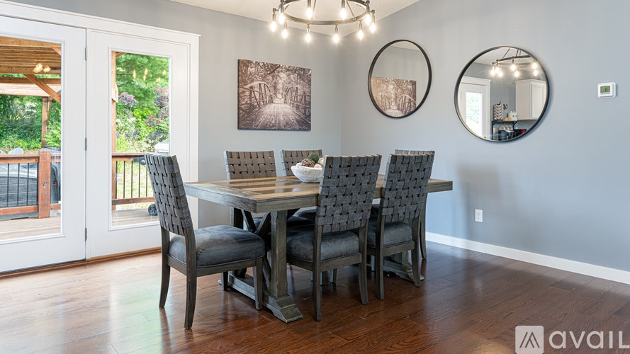 A dining room with a table and chairs and a balcony outside.