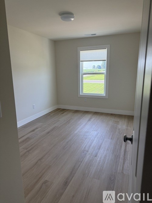 A room with a window and wooden flooring.