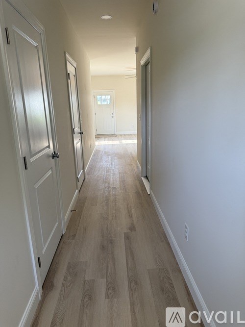 A long hallway with wood floors and white walls.