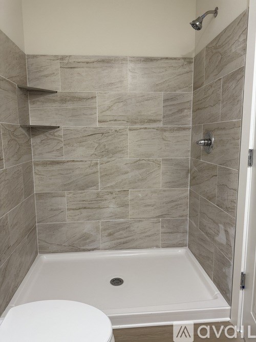 A bathroom with a toilet, tub, and tiled walls.