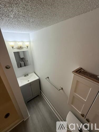 A small bathroom with a toilet, sink, and cabinet.