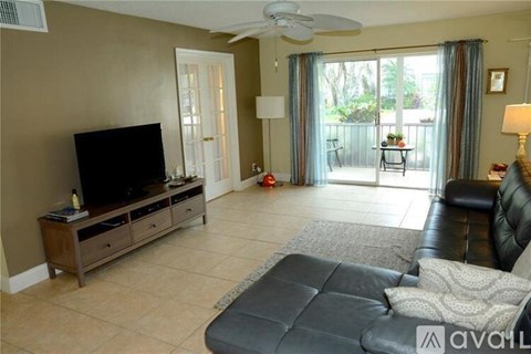 A living room with a black leather couch and a flat screen TV.