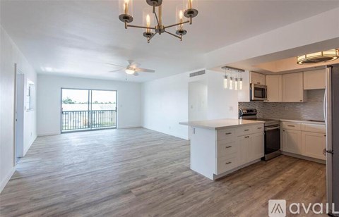 A well-lit kitchen with white cabinets and a wooden floor.
