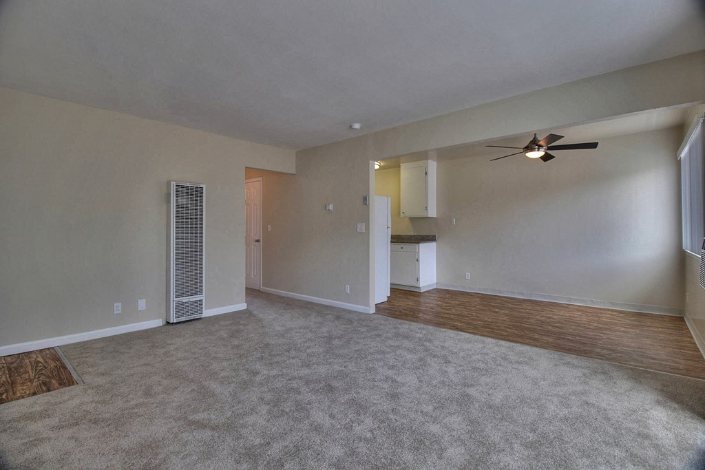 an empty living room with a ceiling fan