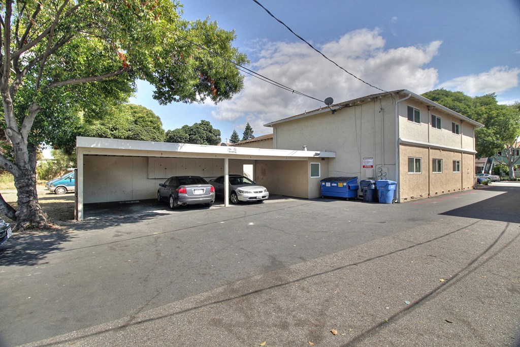 a large white building with a parking lot with cars