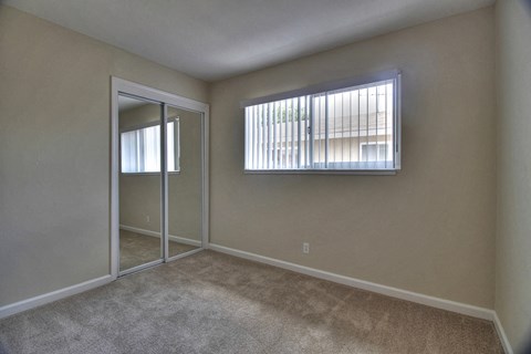 an empty bedroom with a window and a door to a closet