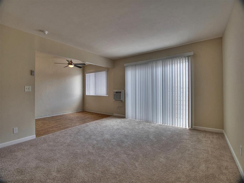 an empty living room with a window and a ceiling fan