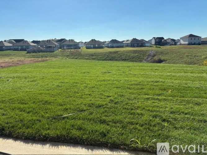 A grassy field with a row of houses in the background.