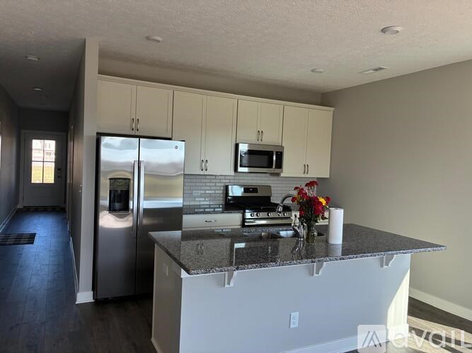 A kitchen with a refrigerator, microwave, and oven.