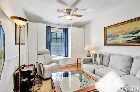 A living room with a grey couch, a chair, a coffee table, and a painting on the wall.