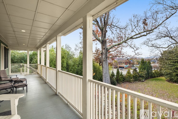 A white porch with a bench and trees in the background.