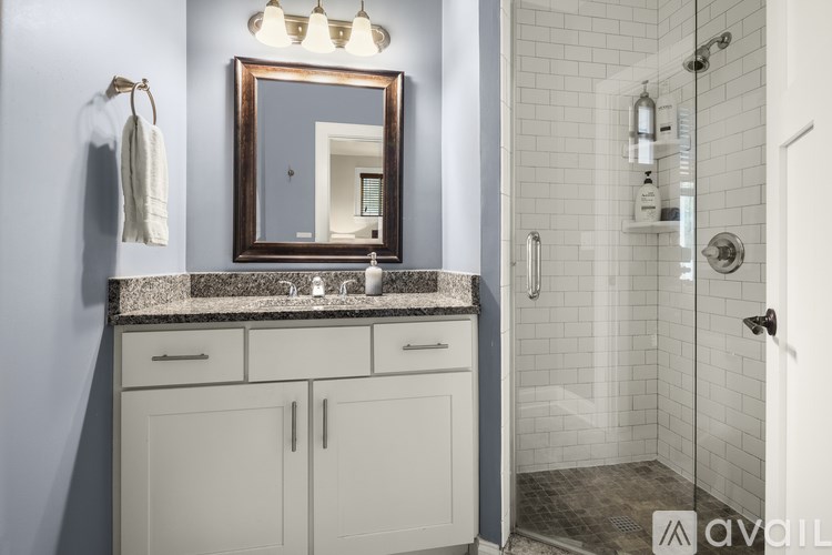 A bathroom with a mirror, sink, and shower.