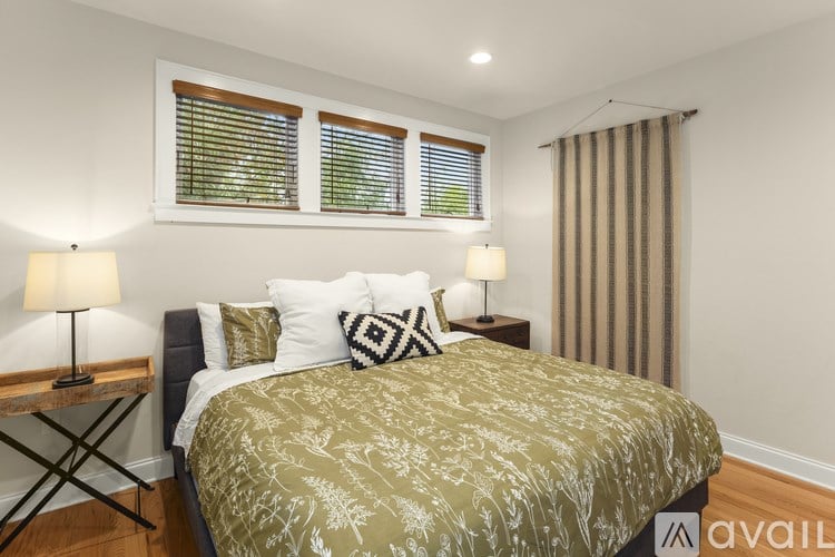 A bedroom with a bed, two lamps, and a window with blinds.
