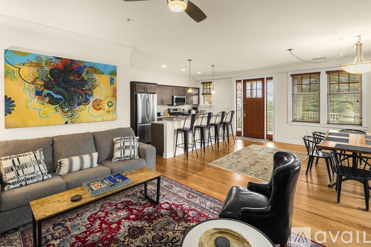 A living room with a grey couch and a large painting on the wall.