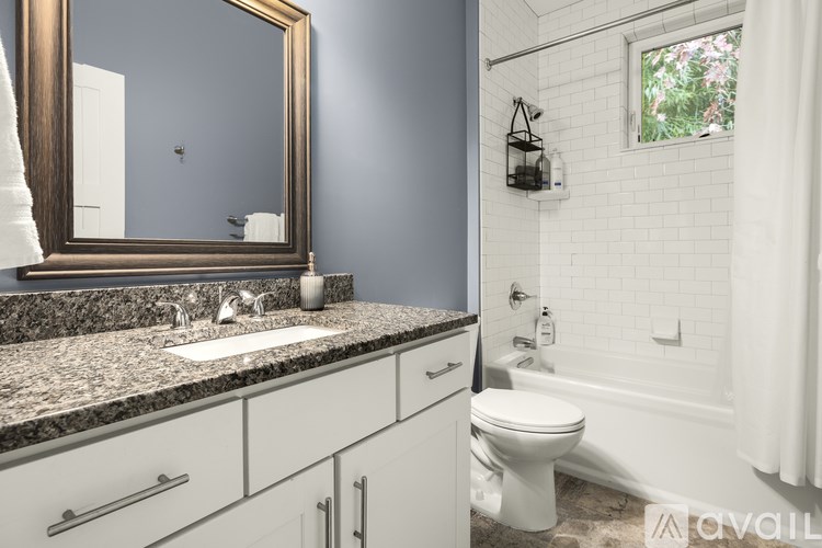 A bathroom with a marble countertop and white fixtures.