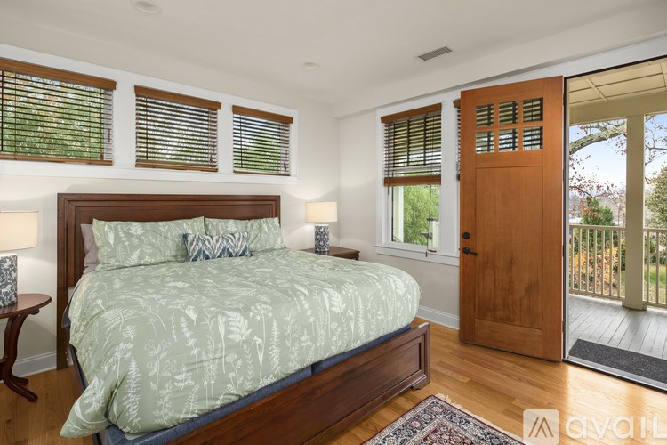 A bedroom with a bed, nightstand, and window with blinds.