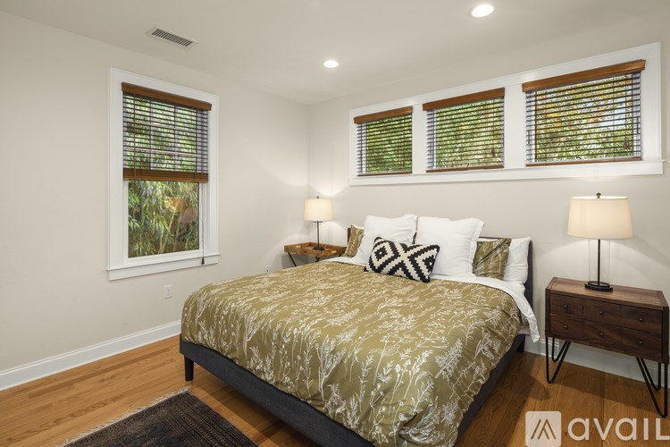 A bedroom with a bed, two lamps, and a window with blinds.