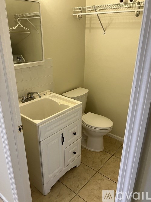 A white bathroom with a toilet, sink, and a mirror.