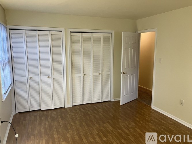 A room with white closet doors and a wooden floor.