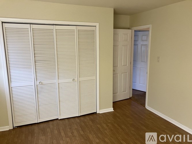 Closet with white doors and a white door in the background.