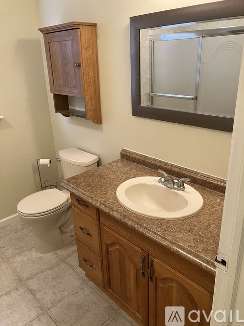 A bathroom with a toilet, sink, and medicine cabinet.