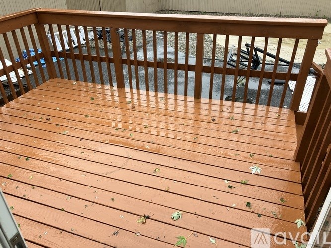 A wooden deck with a railing and leaves on it.