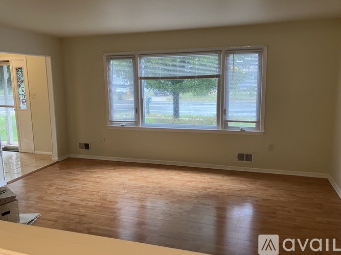 A room with wooden floors and a large window overlooking a street.