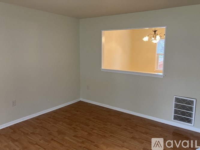 A room with wooden flooring and a window with blinds.