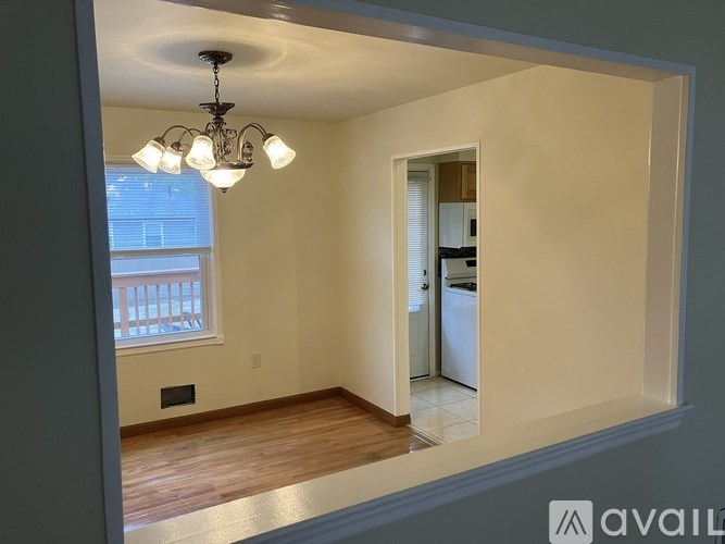 A room with a chandelier and a window with blinds.