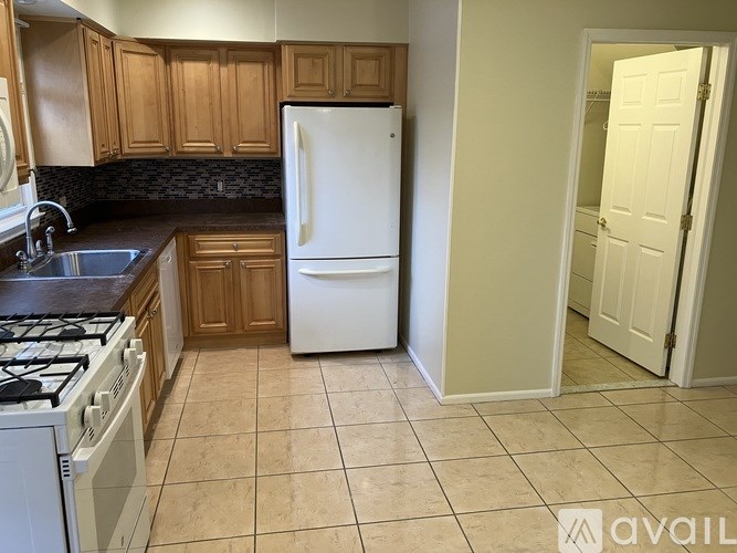 A kitchen with a white refrigerator and wooden cabinets.