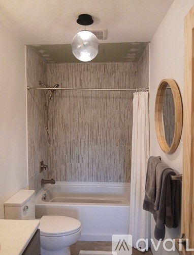 A bathroom with a toilet, a bathtub, and a mirror.