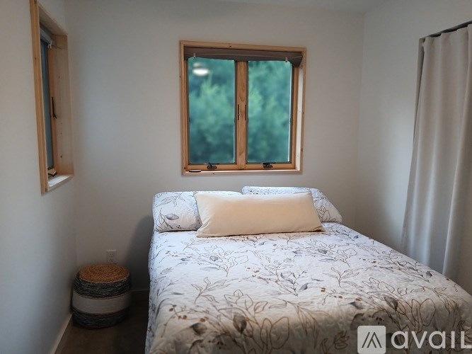 A bedroom with a bed, a window, and a small stool.