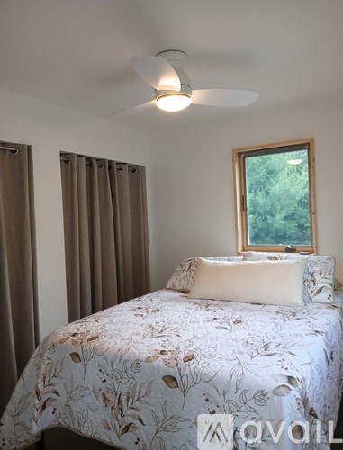 Bedroom with a bed, window, and curtains.