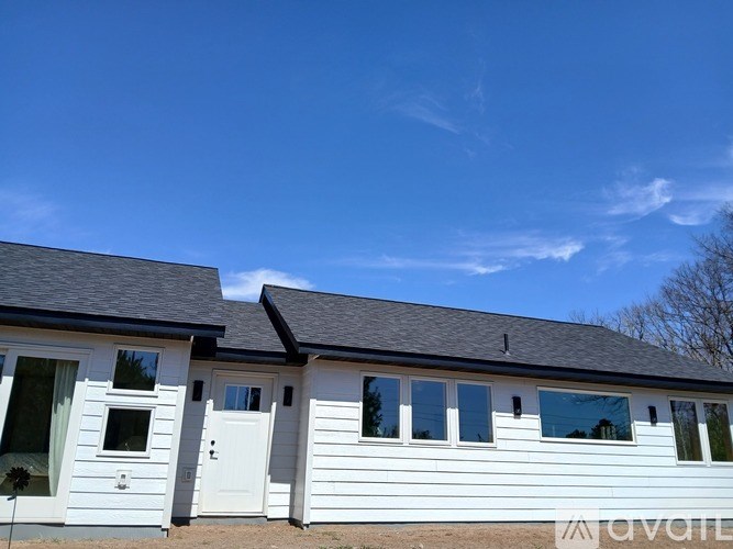 Two white houses with windows and doors are under a clear blue sky.