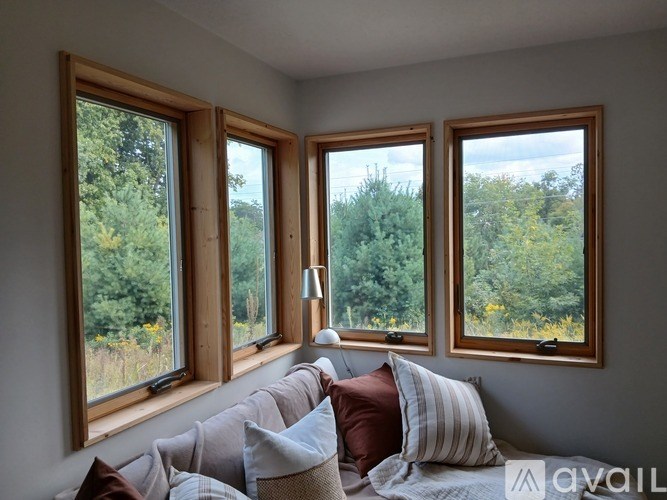 Three windows with pillows on a bed in front of them.