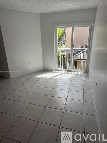 A room with tiled flooring and a sliding glass door leading to a balcony.