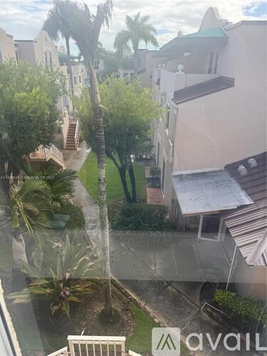 A view of a courtyard with a palm tree and a building with a balcony.