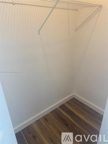 A white wall with a wooden floor and a metal rack.