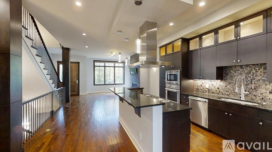 A modern kitchen with dark wood floors and stainless steel appliances.