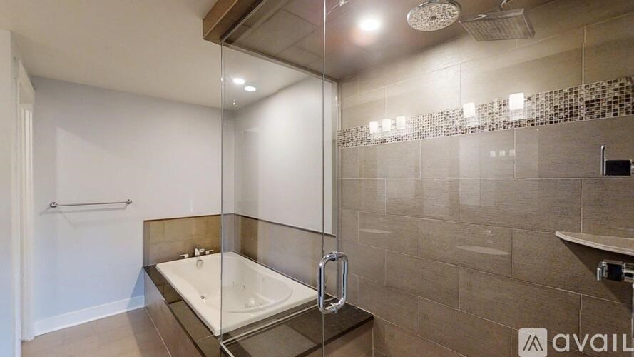 A modern bathroom with a glass shower door and a glass-topped bathtub.